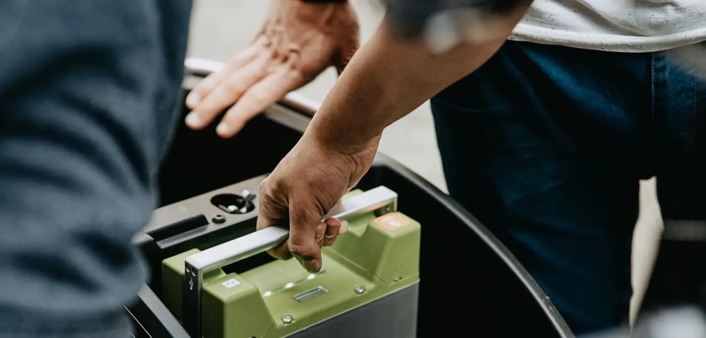 Two people handling a large rechargeable battery pack.